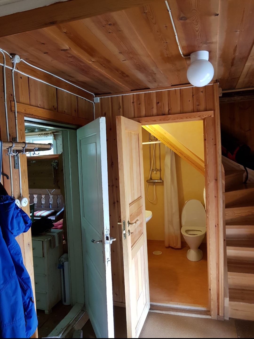 Hallen med klädhängare och dörren in till toaletten med dusch